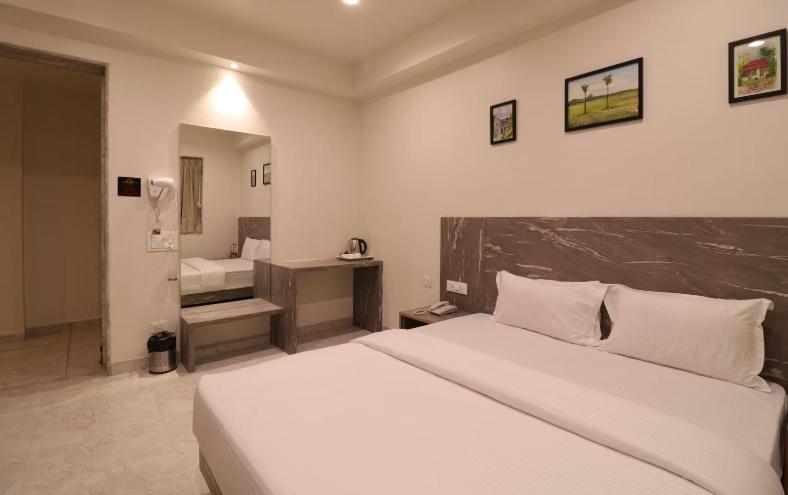 a bedroom with a large white bed and a bathroom at Hotel Jay Palace Inn in Solapur