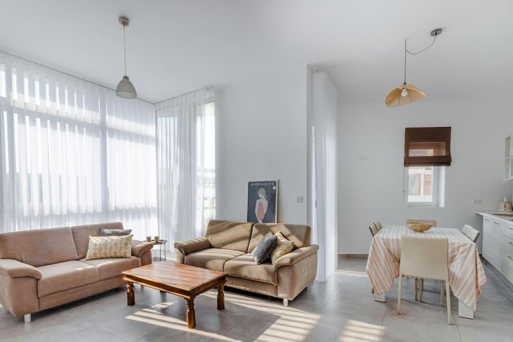 a living room with two couches and a table at Bright Apartment minutes from the Sea in Il-Gżira