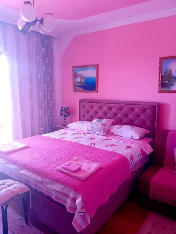 - une chambre rose avec un lit et une chaise dans l'établissement Guest House Cinderella, à Herceg-Novi
