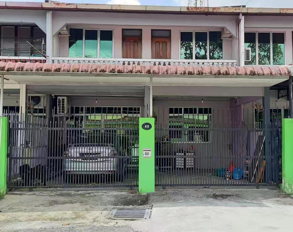 a green gate in front of a house with a car at HM AIRBNB in Sibu
