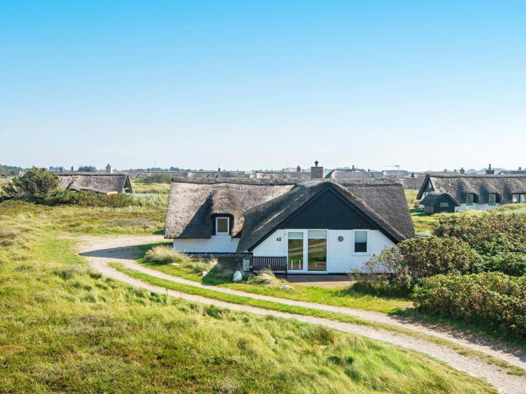 een huis met een rieten dak in een veld bij 8 person holiday home in Ringk bing in Nørre Lyngvig