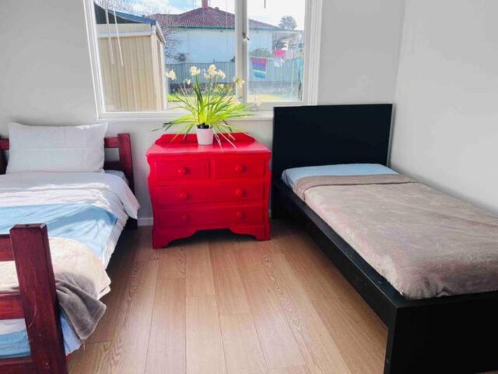 a bedroom with two beds and a red dresser at Twin Room -2single beds in share house in Queanbeyan & Canberra in Queanbeyan