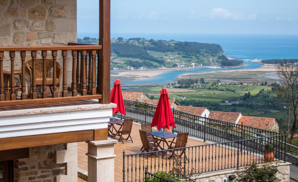 Un balcón con mesas y sillas y vistas al océano. en Hotel Mirador de Moriyón en Miravalles
