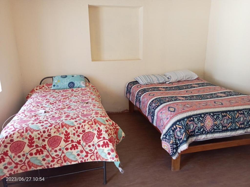 a bedroom with two beds and a mirror at La casa de Yllari in Cusco