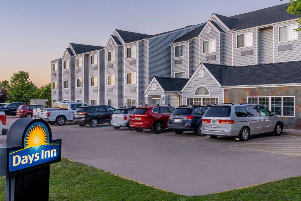 un gran edificio con coches estacionados en un estacionamiento en Days Inn & Suites by Wyndham Greeley en Greeley