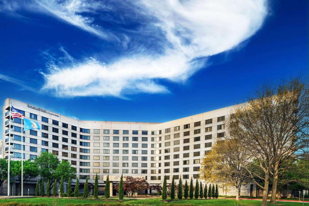 a large building with an american flag in front of it at DoubleTree by Hilton Tulsa at Warren Place in Tulsa