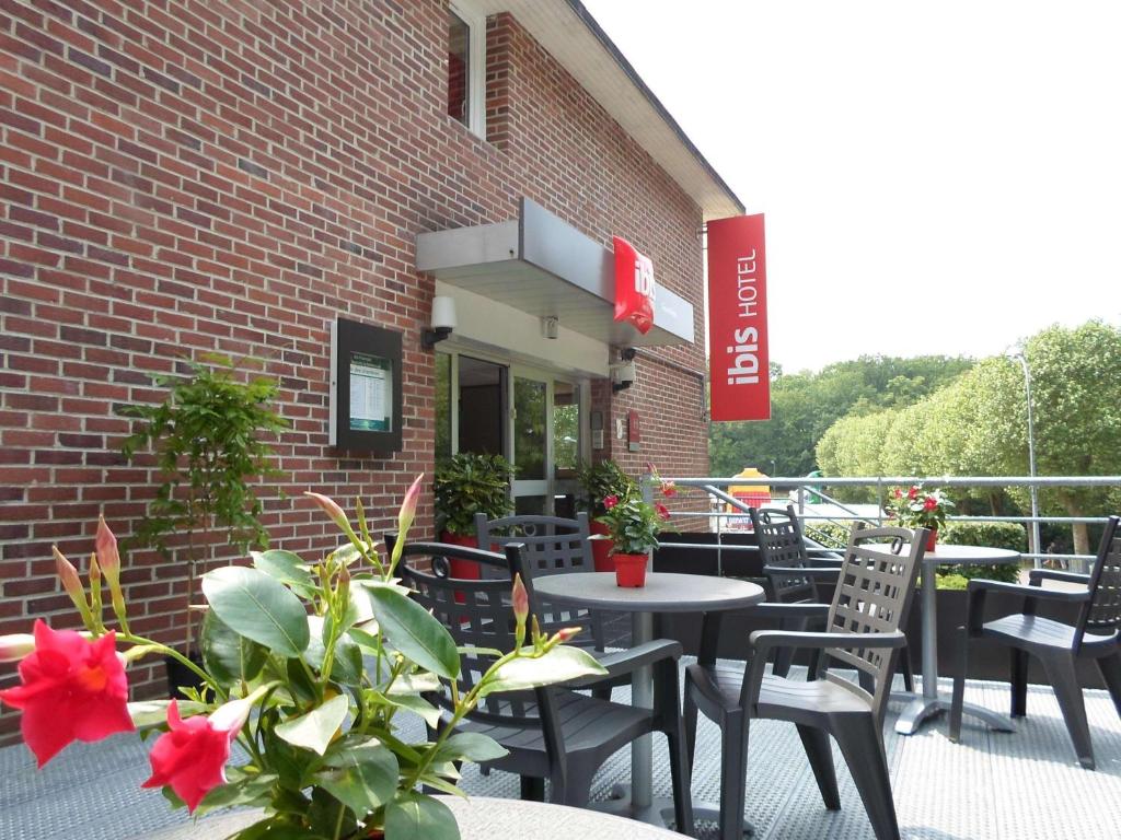 un patio avec des tables et des chaises devant un bâtiment en briques dans l'établissement ibis les Etangs des Moines, à Fourmies