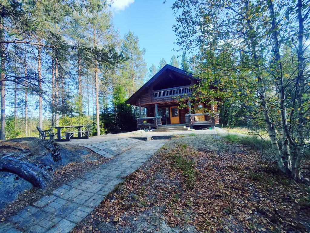 una cabaña de madera en el bosque con mesa de picnic y banco en Kalliorinteen Mökit Ruskapirtti en Töysä