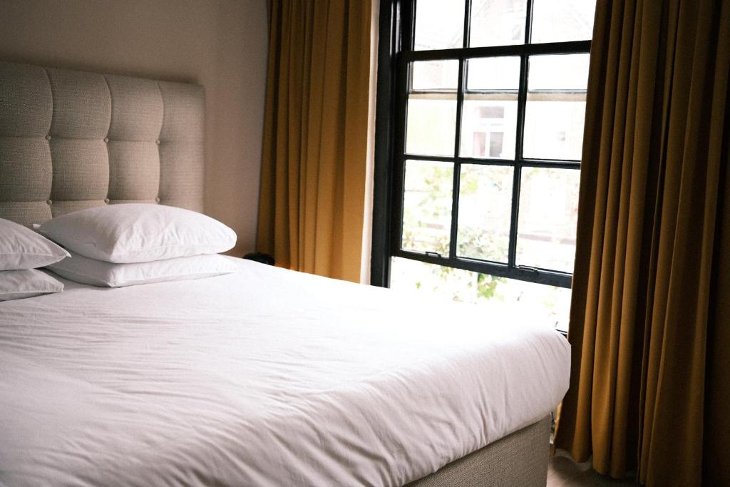 a bedroom with a white bed and a window at Boutique Hotel Johannes in Delft