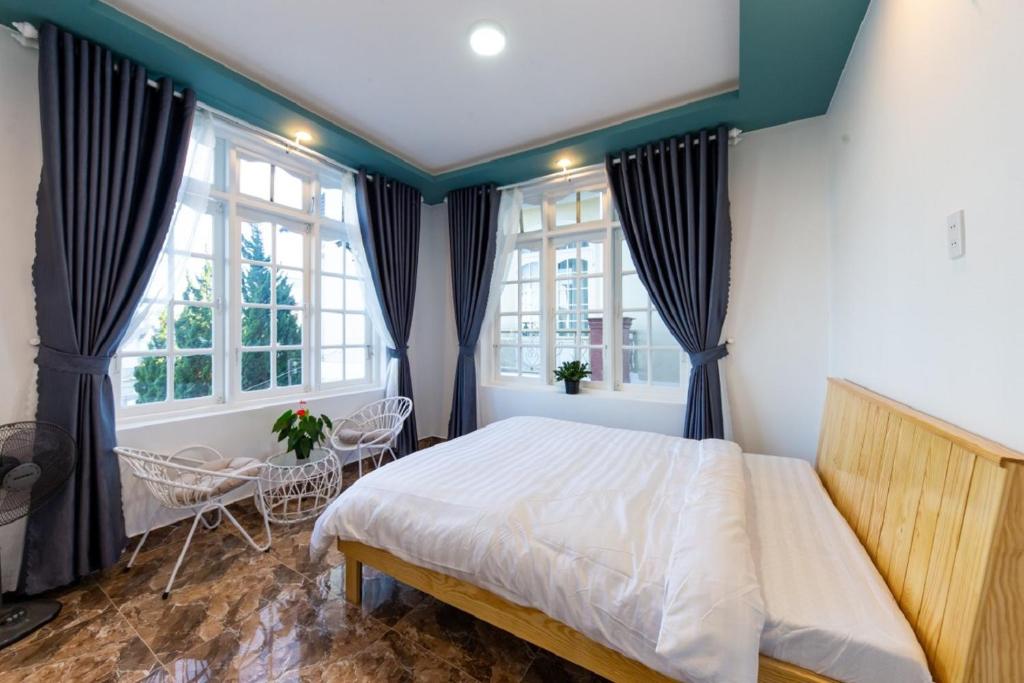 a bedroom with a bed and two windows at Trà My Villa Đà Lạt in Da Lat