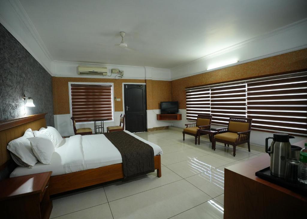 een hotelkamer met een bed en stoelen en een televisie bij Hotel Maharani in Pala
