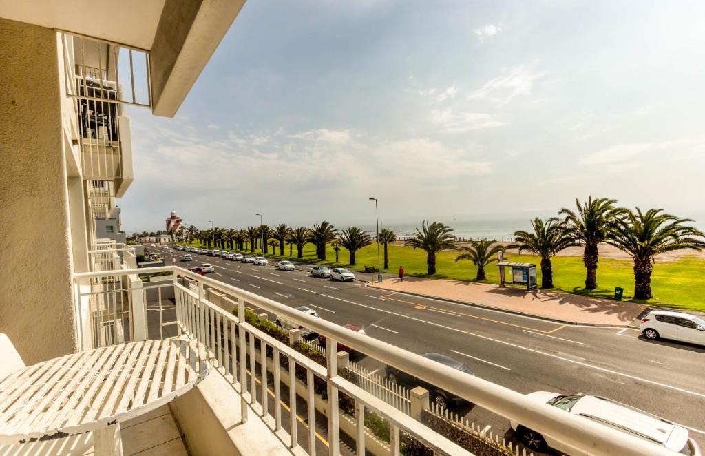 a balcony with a view of a road and palm trees at Mouille Point Places - Studios & Apartments in Cape Town