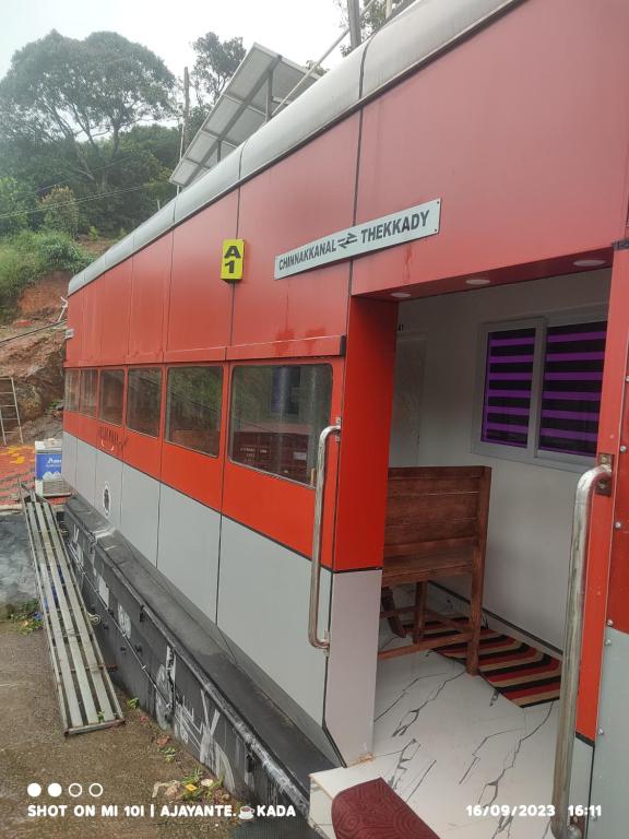 een rode en witte trein op een treinstation bij Naturehive in Idukki