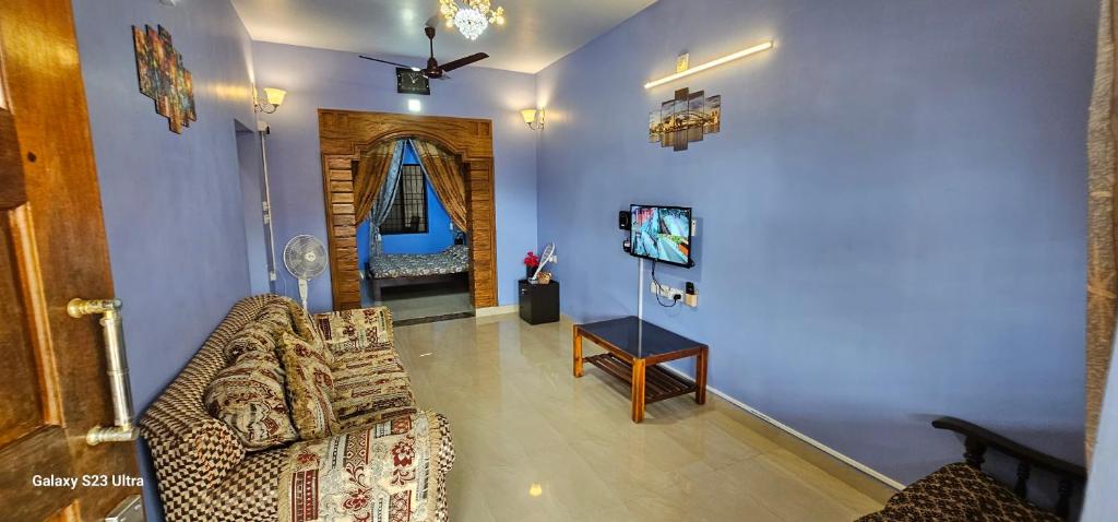 ein Wohnzimmer mit einem Sofa und einem TV in der Unterkunft UDUPI HOMESTAY - Hill Top Villa - Dendoorkatte in Udupi