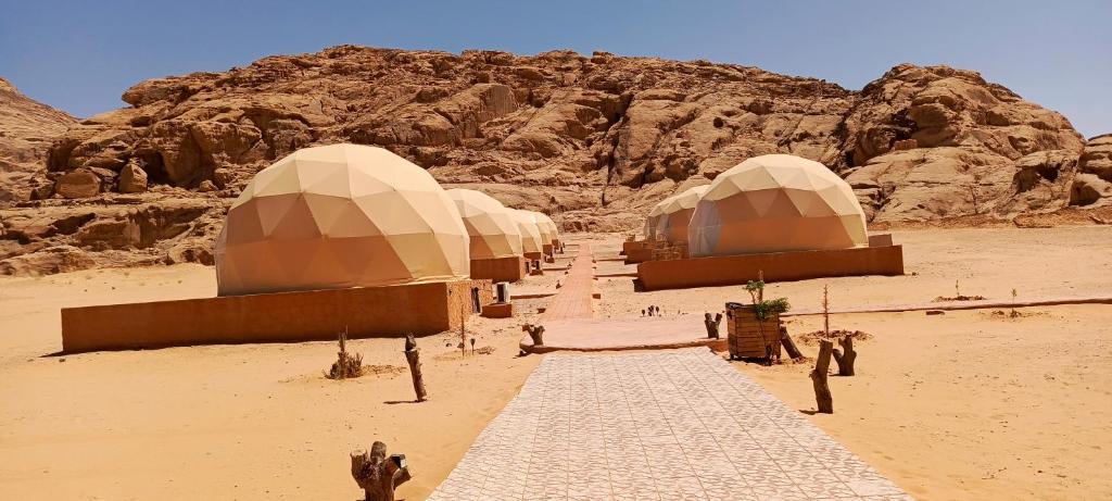Una fila de cúpulas en un desierto con una montaña en Wadi Rum Marcanã camp, en Áqaba