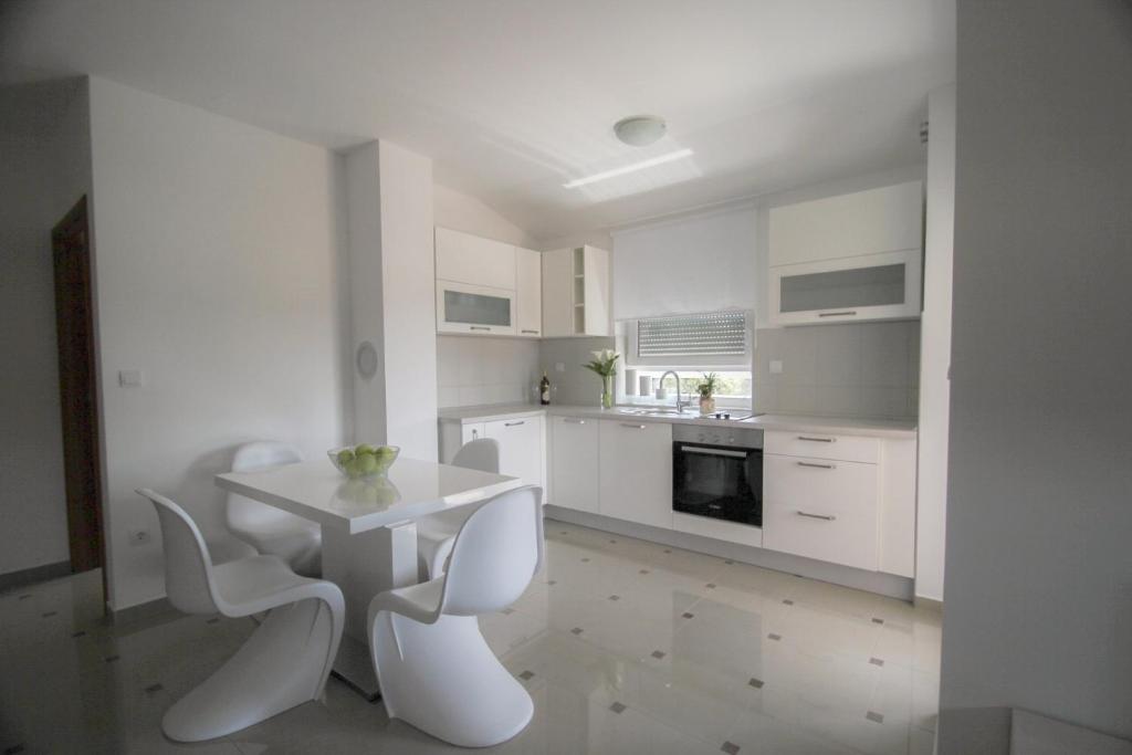 a white kitchen with a white table and white chairs at Apartment Matea in Banjole