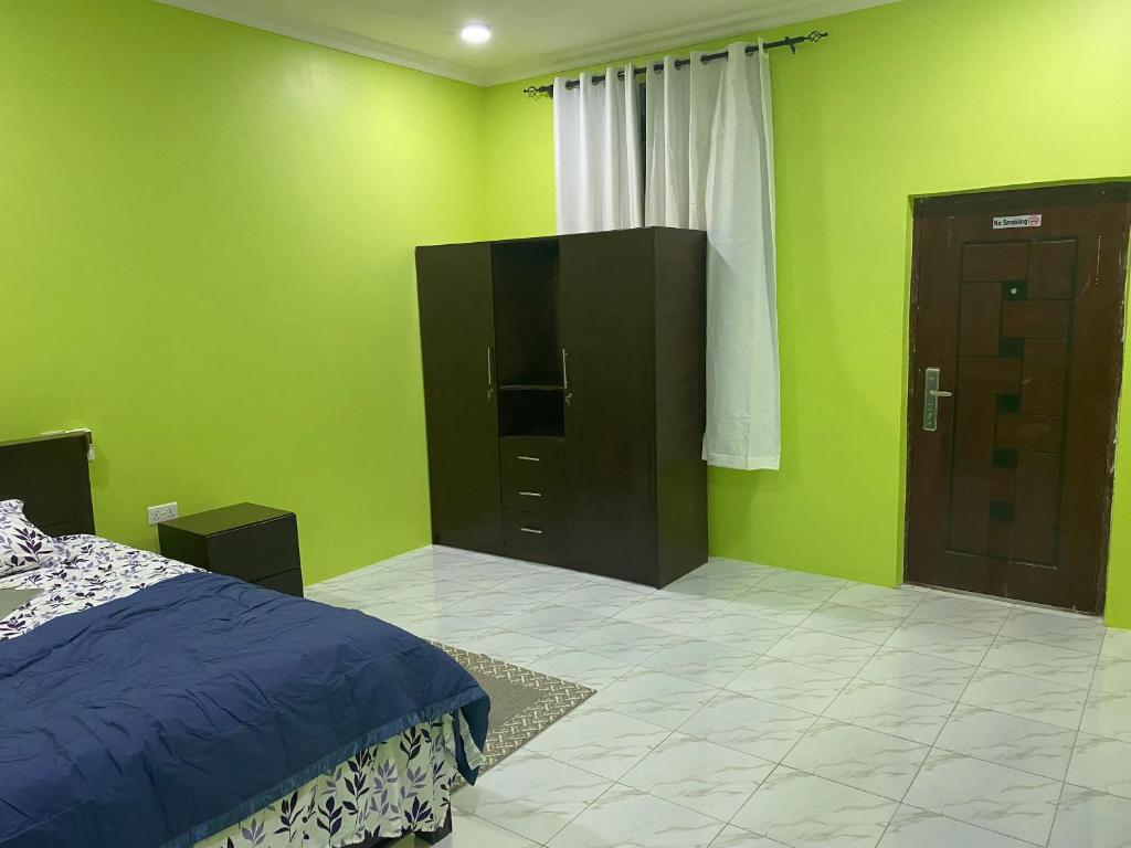 a bedroom with green walls and a bed and a door at Oneworld Guesthouse & and Events Centre in Accra
