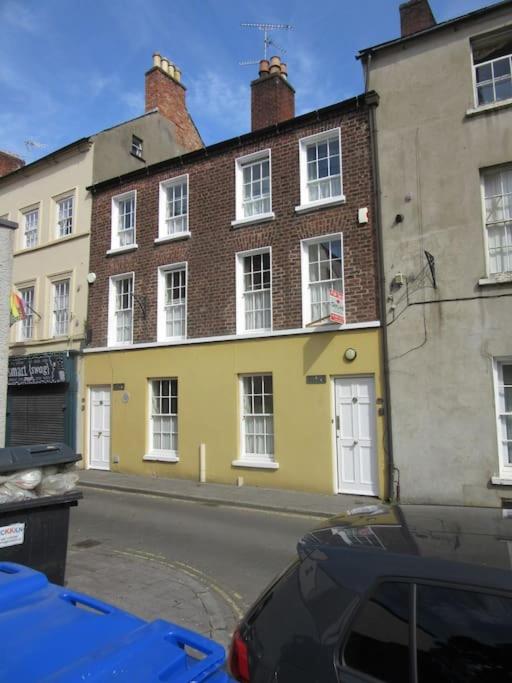a yellow building on the side of a street at Cathedral Cottage in Derry Londonderry