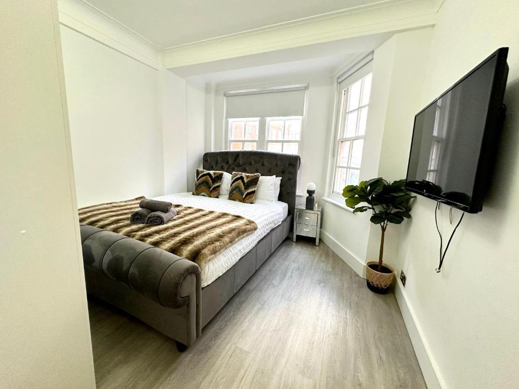 a bedroom with a bed and a flat screen tv at Vibrant 2-Bedroom Flat with Elevator in Marylebone, Close to Hyde Park & Edgware Road in London