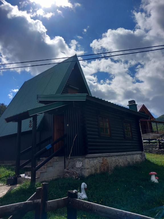 a wooden house with a green roof on a field at Odmor in Šavnik