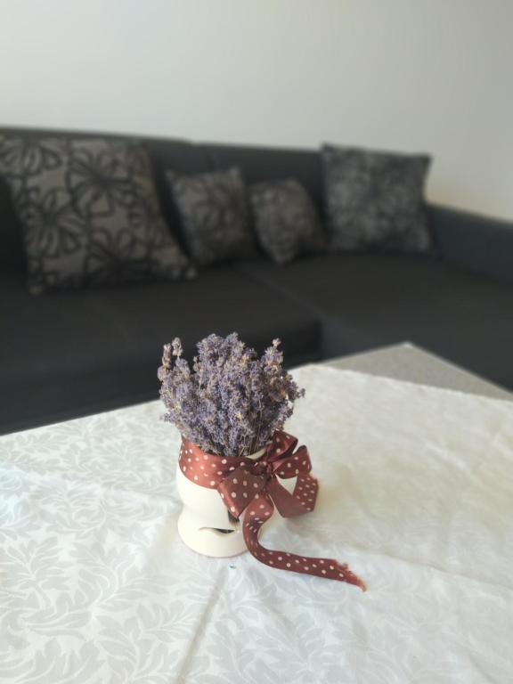 un jarrón lleno de flores púrpuras sentado en una cama en Sweet Home Appartman, en Kazincbarcika
