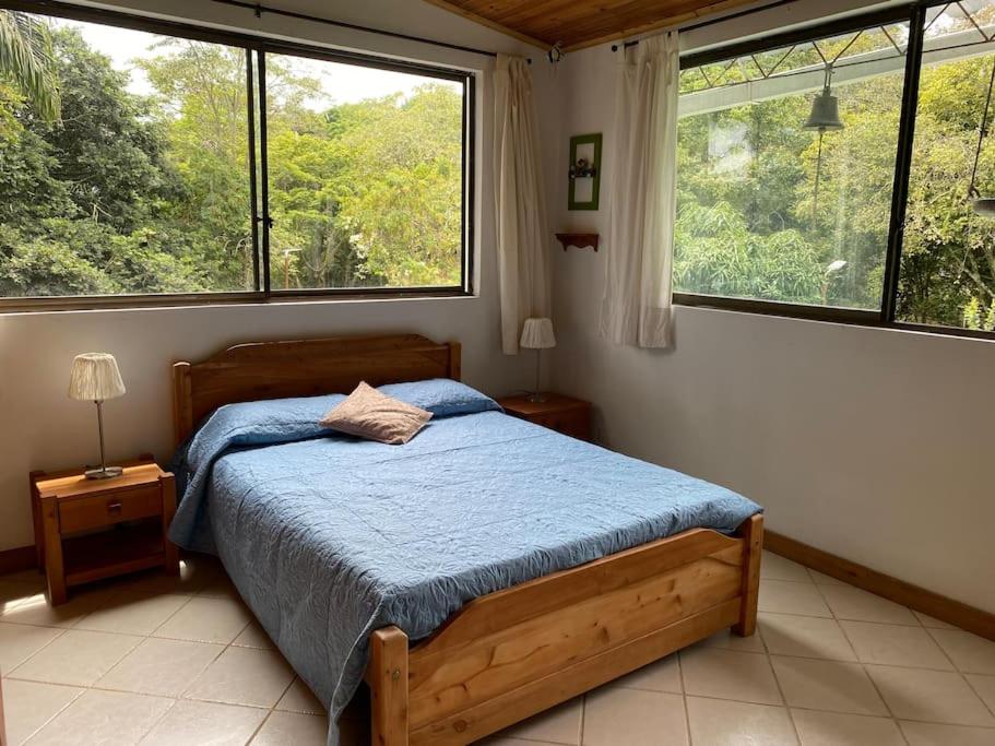 een slaapkamer met een bed met een blauw dekbed en 2 ramen bij Casa de campo Cutucumay in Chinauta