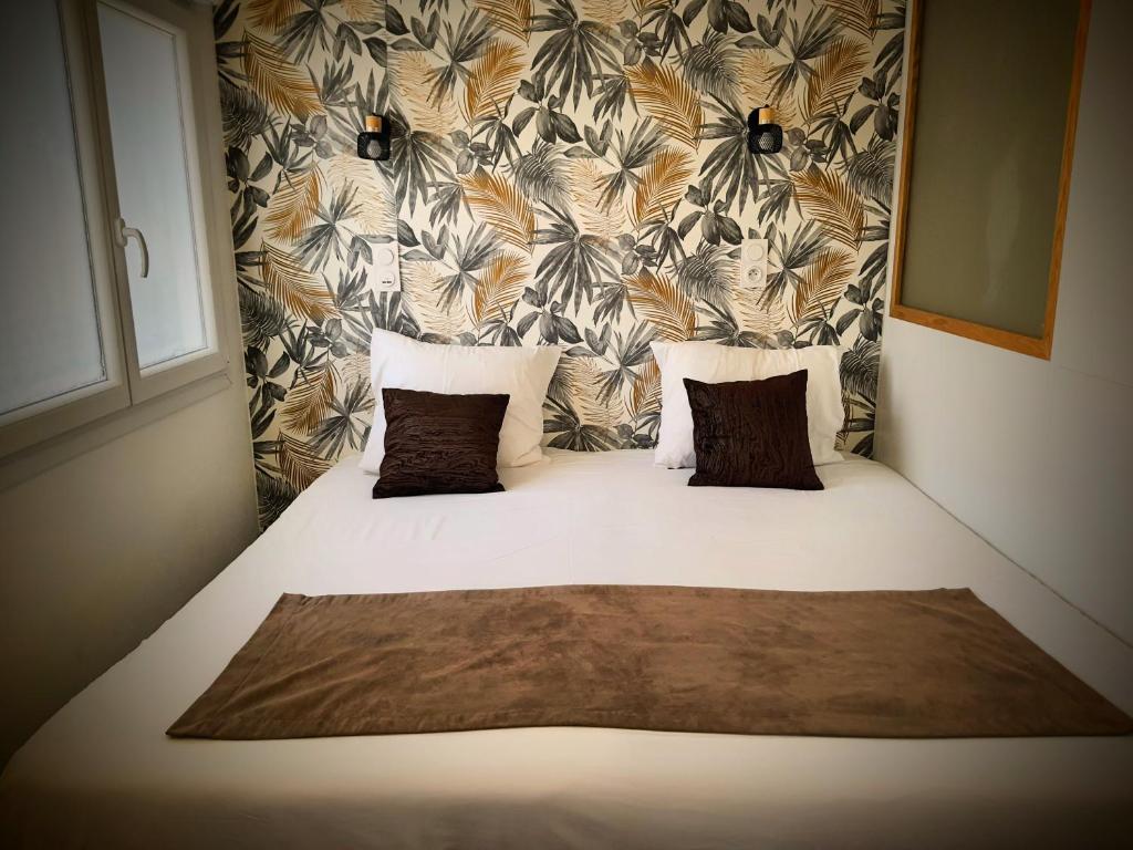 a bed with three pillows on it in a bedroom at Cosy Aulnay-Paris Nord -Expo Villepinte in Aulnay-sous-Bois