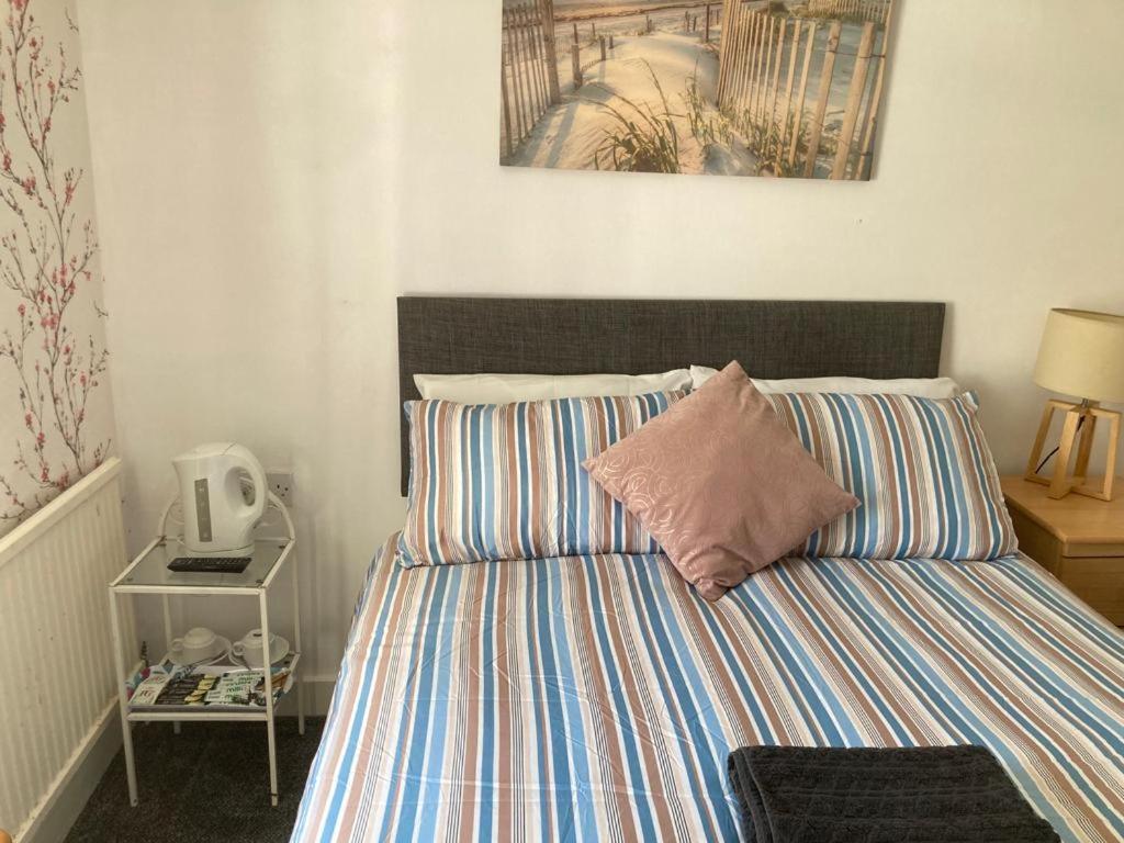 Holland arms hotel في Llangristiolus: سرير مع لحاف مخطط في غرفة النوم