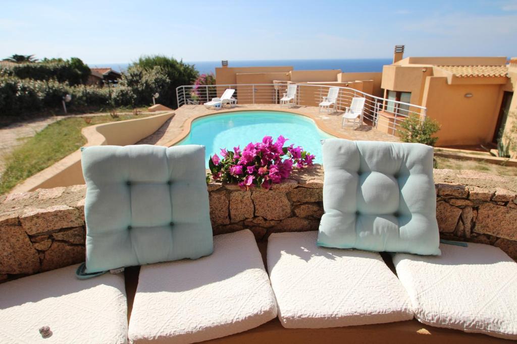 2 sillas sentadas en una pared junto a una piscina en Residence La Cala infinityholidays, en Costa Paradiso