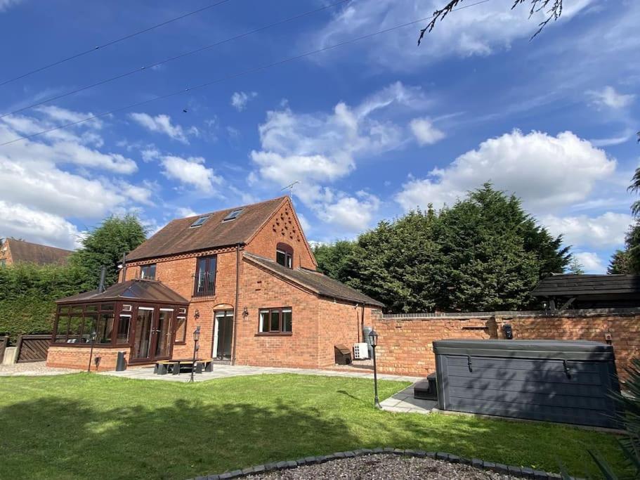a large brick house with a grass yard at The Coach House by Phoenix Premises - Hot Tub Fire Pit BBQ Log Burner Bar Games Room in Birmingham
