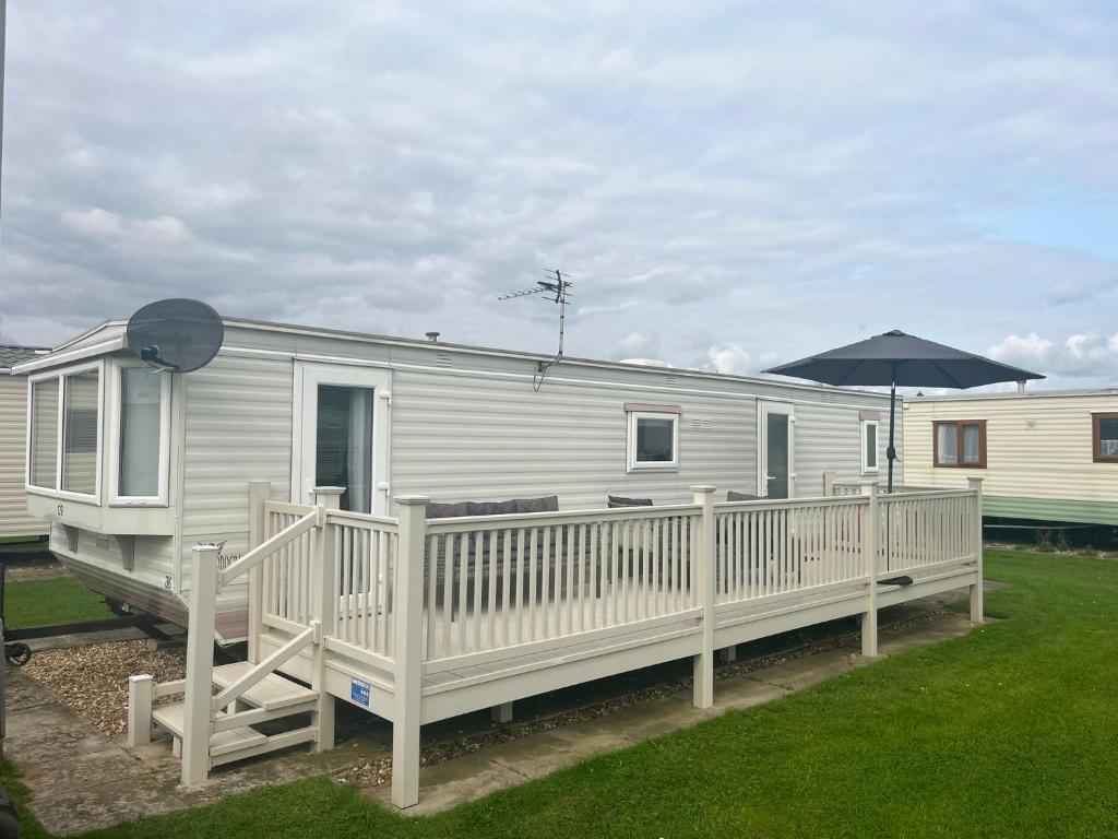 a mobile home with a porch and an umbrella at GB36 in Chapel Saint Leonards