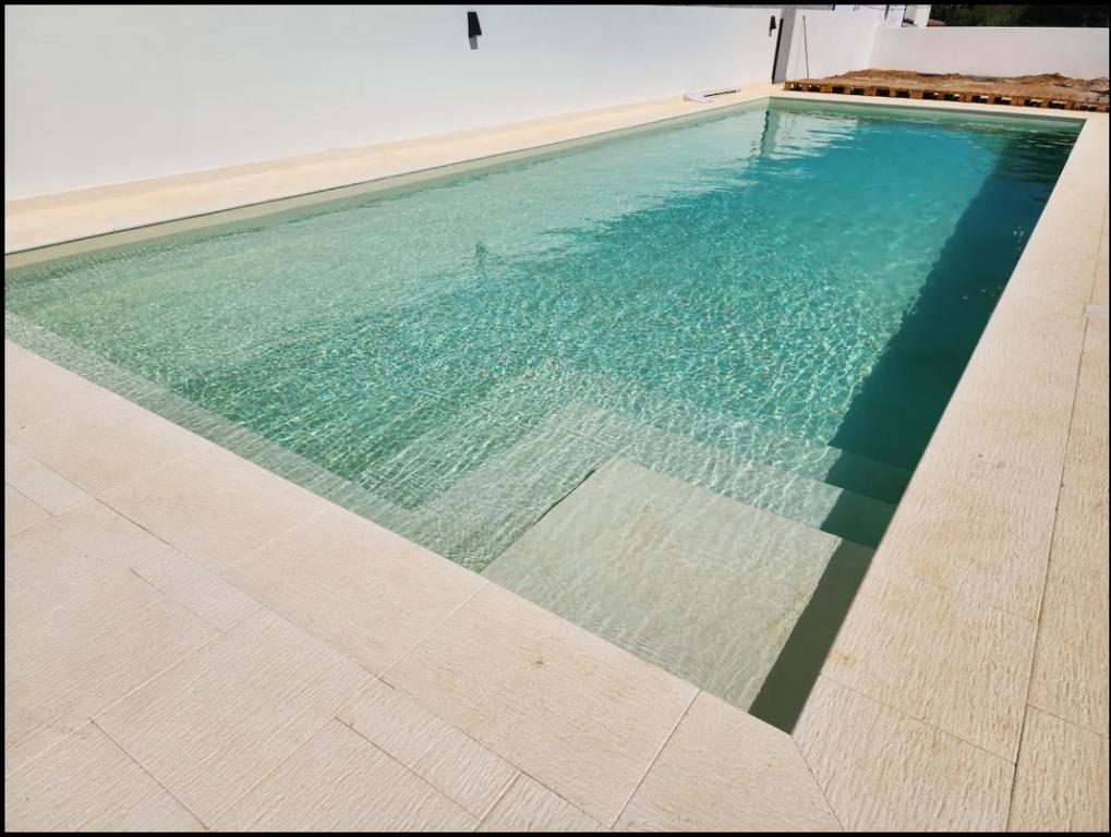a swimming pool with turquoise blue water at Luz Do Sul Holiday Rental - Pedras in Moncarapacho