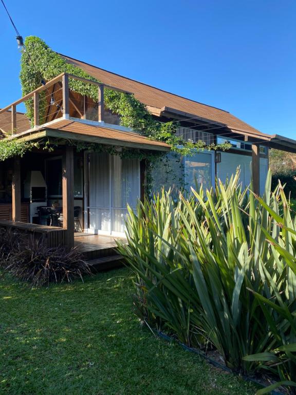 a house with a wrap around porch with plants at Descanso do Rosa - cabanas charmosas in Imbituba