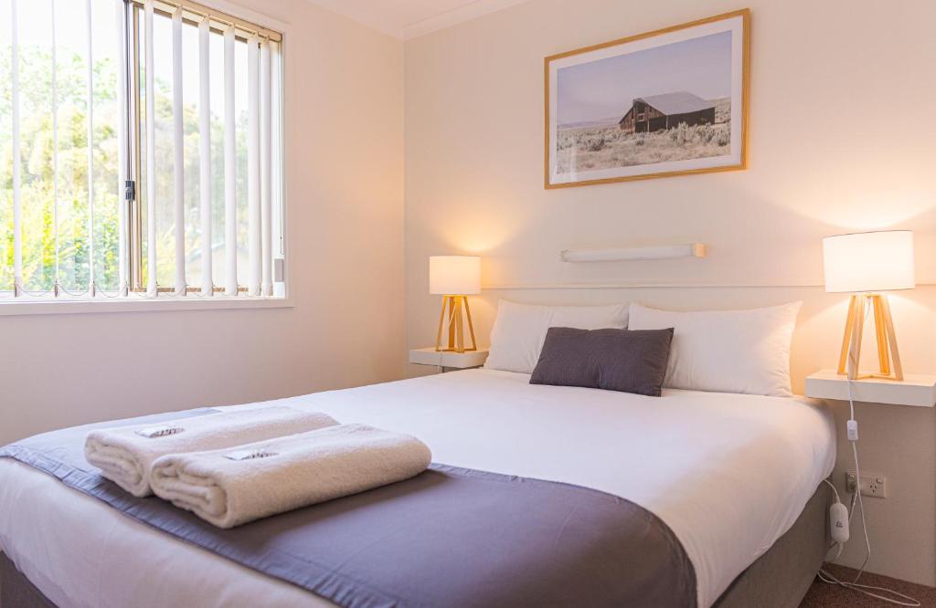 a bedroom with a large white bed with two lamps at Penola Coonawarra Caravan Park in Penola