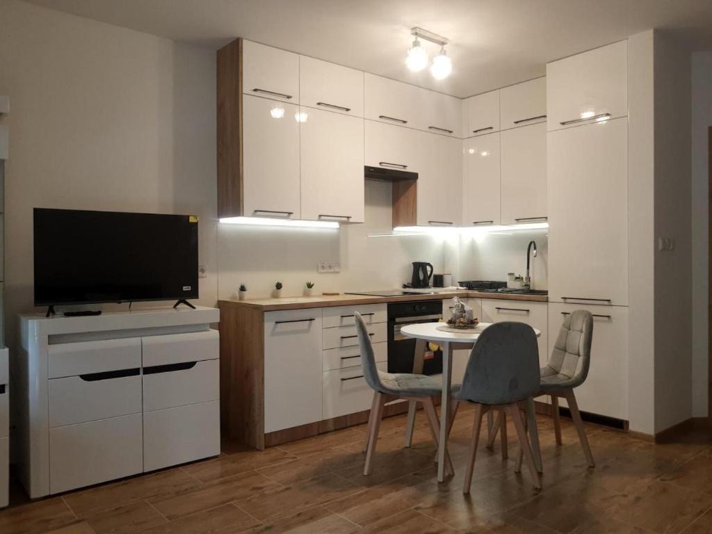a kitchen with white cabinets and a table and chairs at Bounty in Busko-Zdrój