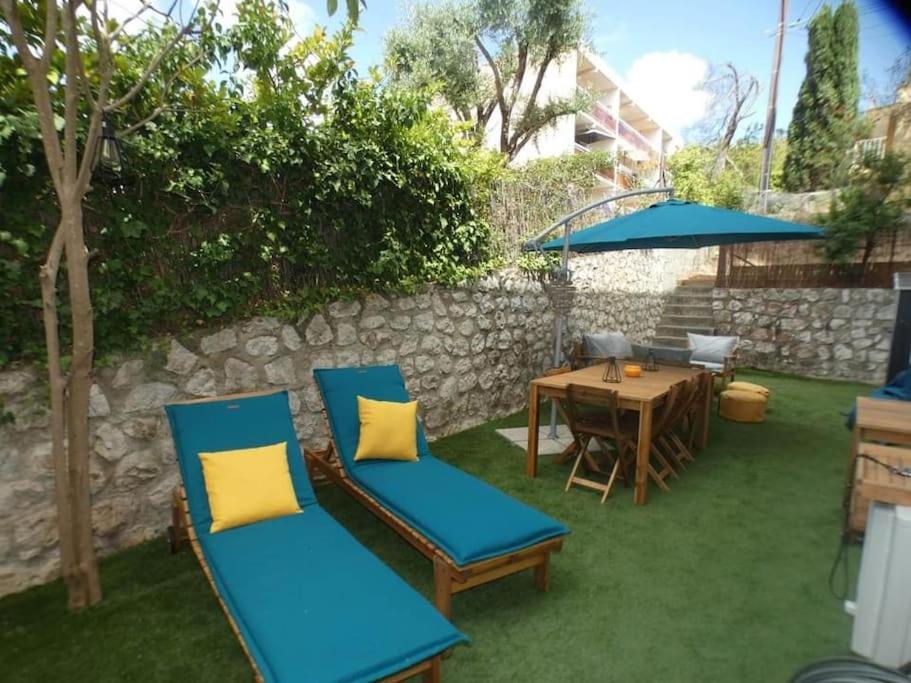 une terrasse avec 2 chaises et une table avec un parasol dans l'établissement Studio avec jardin proche plage Six Fours/Sanary, à Six-Fours-les-Plages