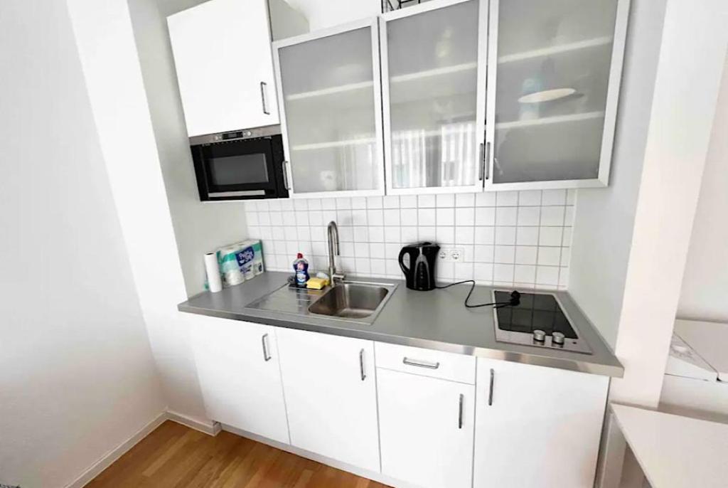 una cocina con armarios blancos y fregadero en Kölner Apartment direkt am Zentrum, en Colonia