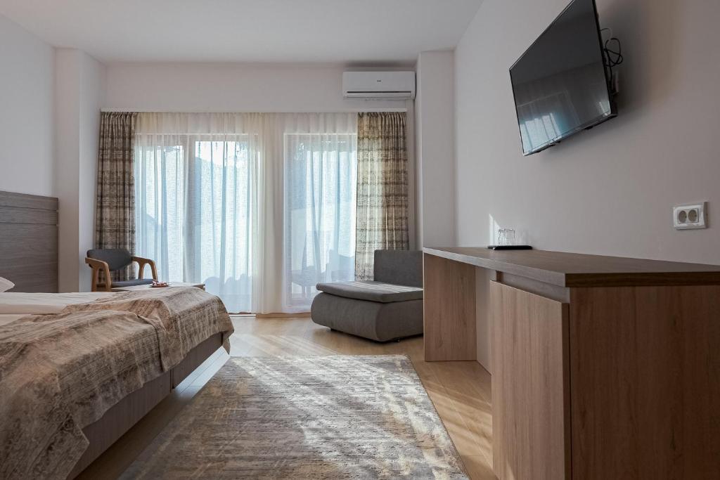 um quarto com uma cama e uma televisão de ecrã plano em Hotel Cascada BAILE OLANESTI em Băile Olăneşti