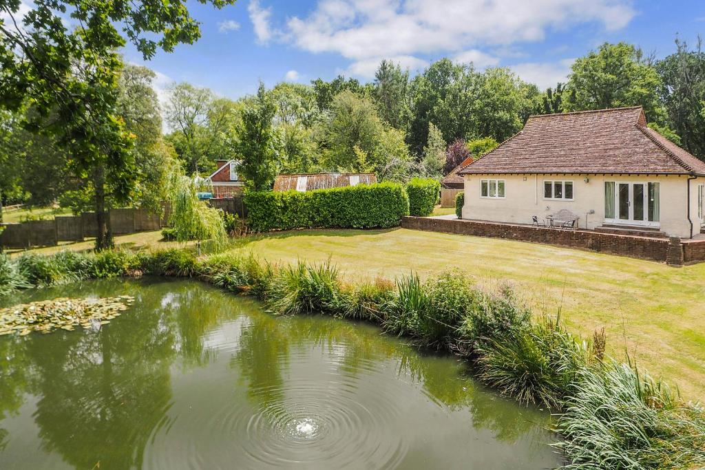 a garden with a pond in front of a house at Woodland Cottage by inspirestays-com in Duneton
