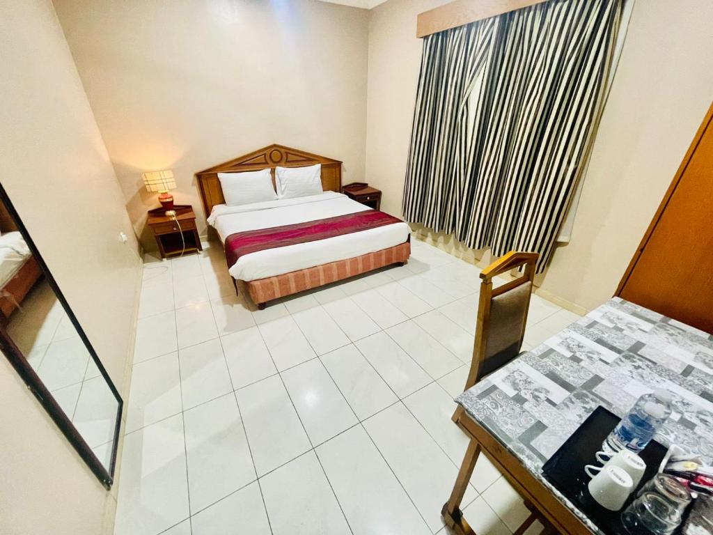 a bedroom with a bed and a desk and a table at Al Ghadeer Hotel Apartment in Sharjah