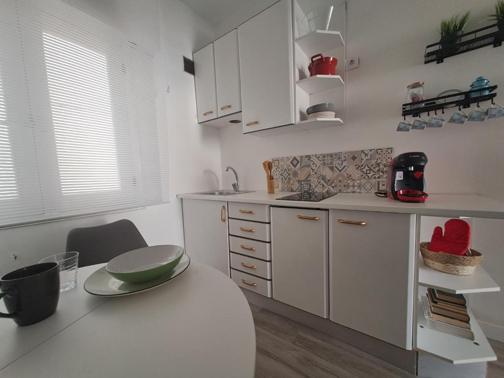 eine Küche mit weißen Schränken und einem Tisch mit grüner Schale in der Unterkunft M&P - Tres Marias Apartments in Redondela