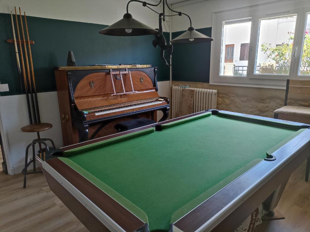 a room with a pool table and a piano at Suite avec billard et jacuzzi in Bergerac