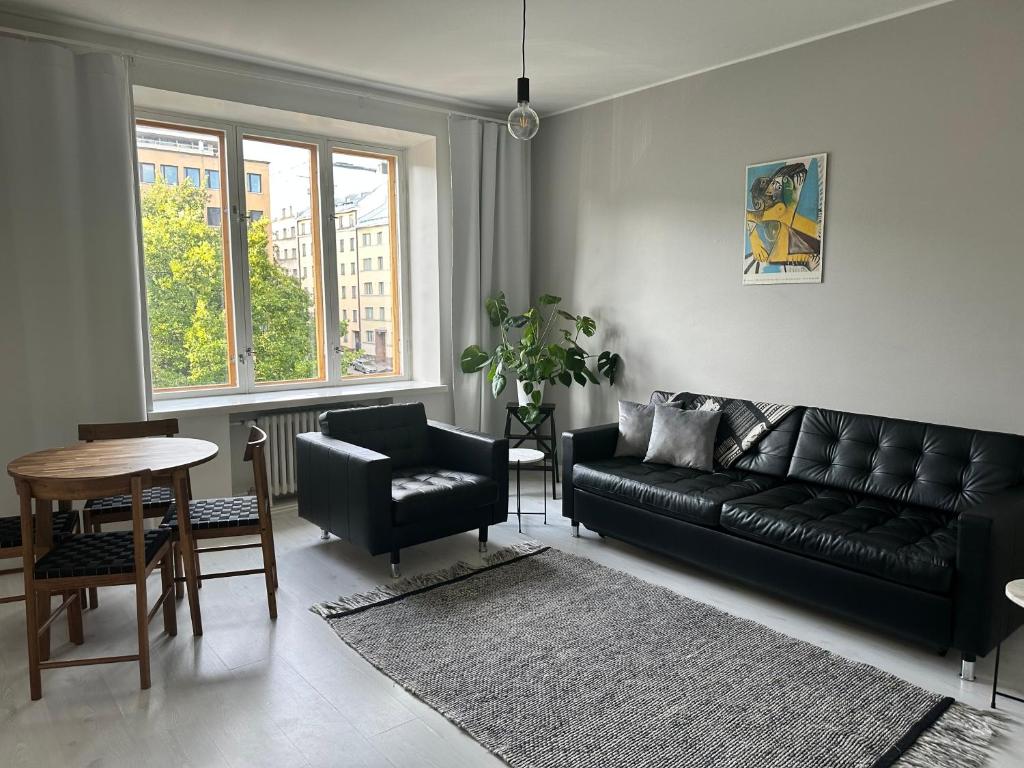 sala de estar con sofá de cuero negro y mesa en Eteläinen Hesperiankatu en Helsinki