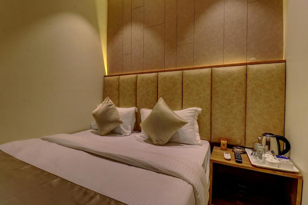 Hotel Amber Suite Near Mumbai Airport في مومباي: سرير في غرفة الفندق مع وسائد عليه