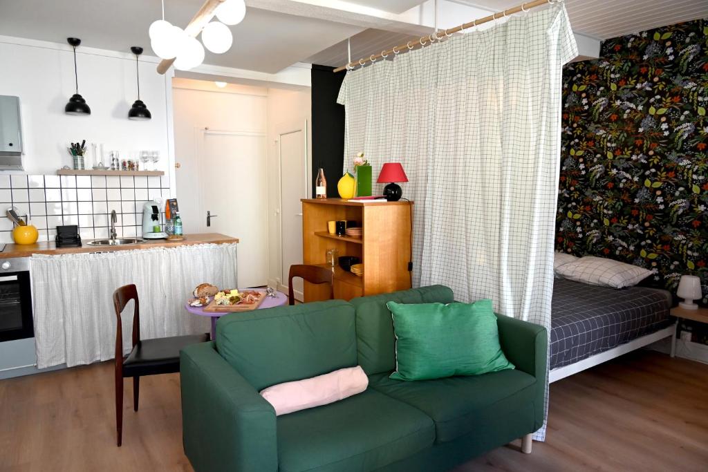 a living room with a green couch and a kitchen at La Gaieté - Meilleurhote-Brioude in Brioude