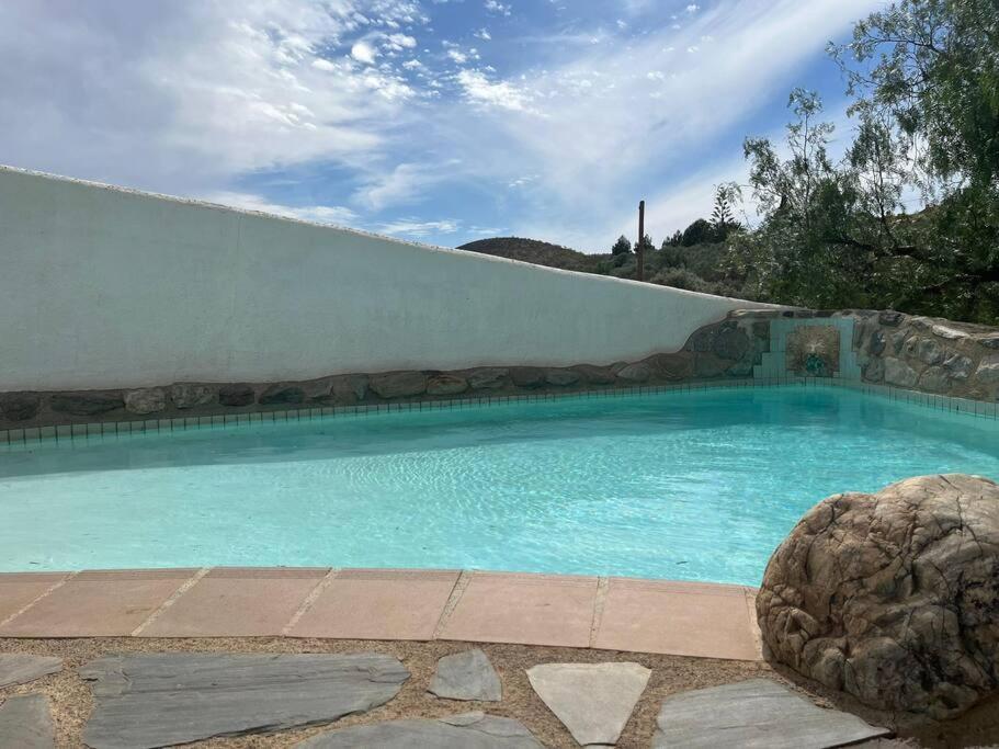 una grande piscina blu con un muro di pietra di La Rama - Wheelchair friendly a Órgiva