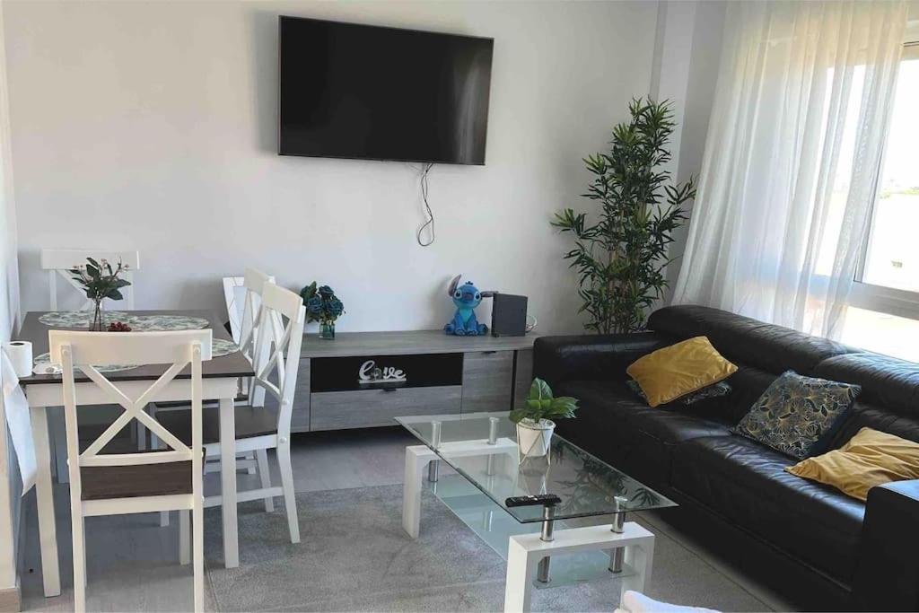 sala de estar con sofá negro y mesa en Apartamento en Santander, en Santander