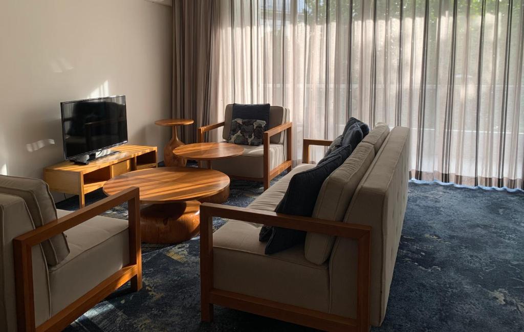 a living room with a couch and chairs and a television at Oasis at Harbour lights Cairns in Cairns