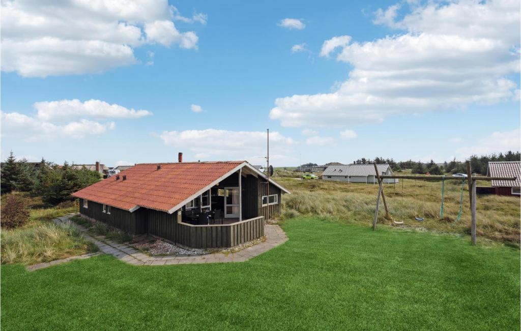 a small house with a red roof in a field at Awesome Home In Hvide Sande With 4 Bedrooms And Sauna in Havrvig