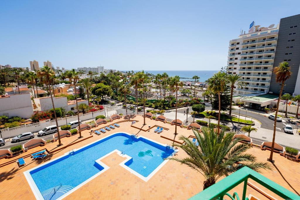 a view of a swimming pool with palm trees and buildings at Las Americas Acapulco 4 Costa Adeje in Playa Fañabe